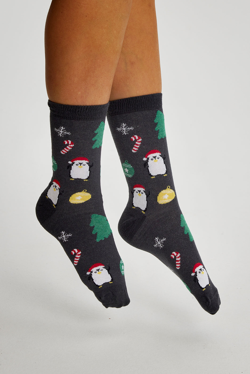 Ett par ben som bär grå julstrumpor med pingviner på.